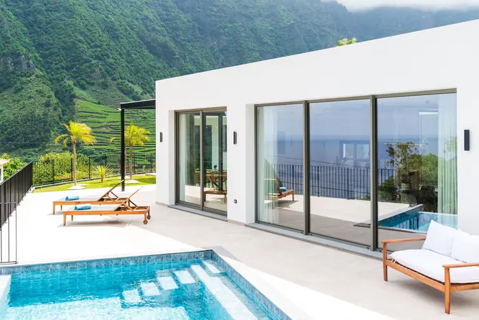 As portas de vidro da moradia abertas para a piscina infinita