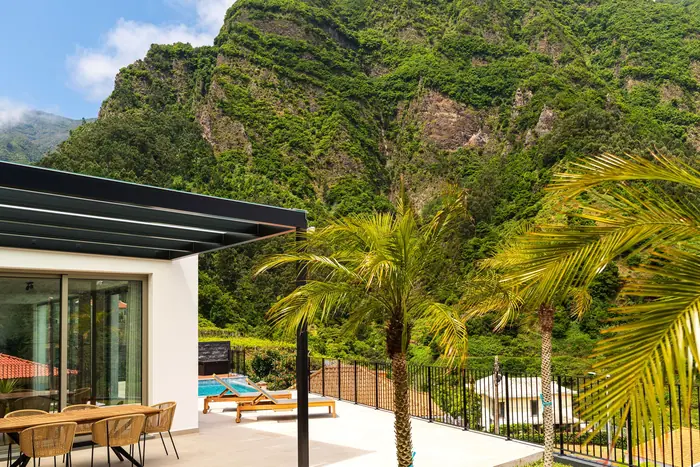Terraço, relvado e palmeiras aos pés da serra